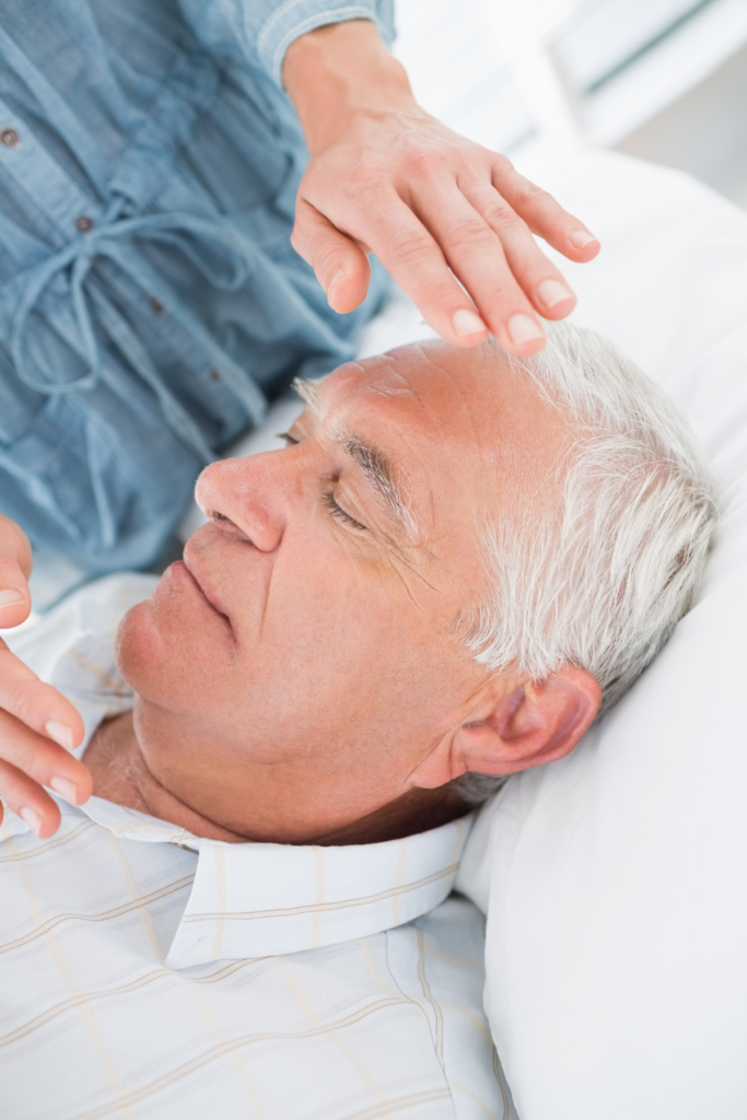 Reiki session on older man to balance his energy and restore harmony to his body.